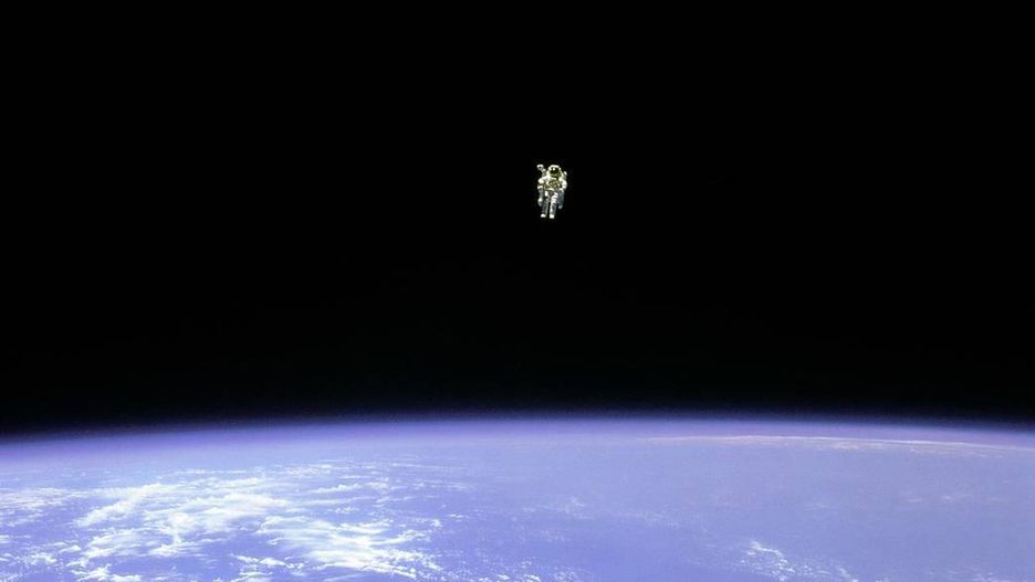 A assustadora e atraente imensidão do espaço em torno do pequeno (mas gigante) Bruce McCandless que realiza o primeiro deslocamento espacial sem amarras. Ele distanciou-se 100 metros de sua nave em 1984.